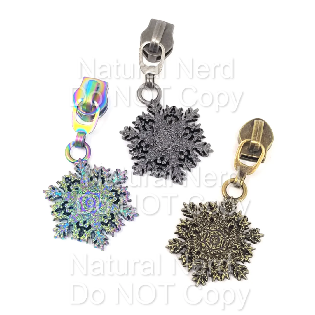 Three snowflake-shaped zipper pulls on a white background.